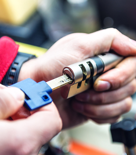 Locksmith inserting a key into a door lock cylinder