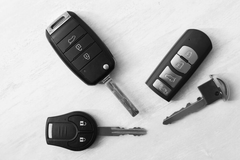 Car keys and remote key fobs on a white surface